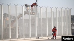 Các công nhân đặt dây thép gai trên một hàng rào dọc theo bến cảng Calais, Pháp, để ngăn chặn di dân nhảy từ xe tải, ngày 7 tháng 9 năm 2016. 