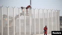 Workers set barbed wire atop a fence along the harbor of Calais, France, to prevent migrants from jumping aboard trucks, Sept. 7, 2016. Britain also plans to build a wall in Calais, part of a security package agreed to by Britain and France.