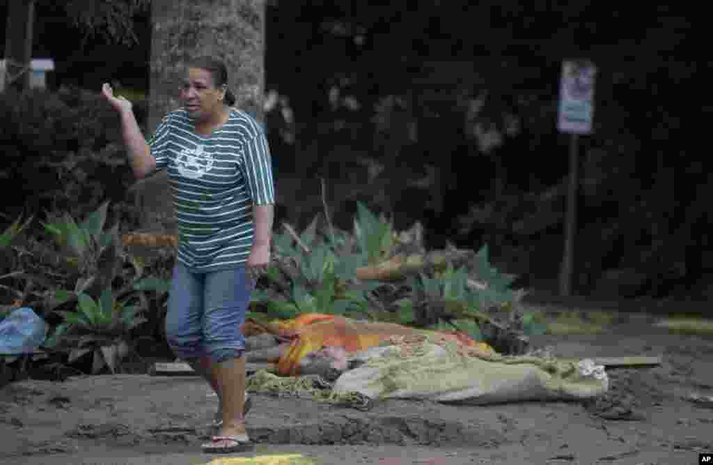 Mulher passa perto de cadáveres de vítimas das cheias, na cidade brasileira de Teresópolis.