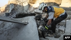 A member of the Syrian Civil Defense, also known as the White Helmets, searches through the wreckage of their center, which was destroyed by government forces in the town of al-Tamana on the southern edges of the rebel-held Idlib province, Sept. 6, 2018.
