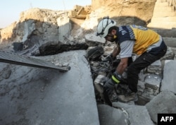 A member of the Syrian Civil Defense, also known as the White Helmets, searches through the wreckage of their center, which was destroyed by government forces in the town of al-Tamana on the southern edges of the rebel-held Idlib province, Sept. 6, 2018.