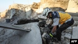 Suriyanın Ağ Dəbilqəlilər kimi tanınan Mülki Müdafiə qrupunun üzvü İdlib vilayətinin Əl-Tamana şəhərində hökumət qüvvələrinin hərbi hava hücumları nəticəsində dağılmış mərkəzlərinin dağıntıları arasında axtarış aparır, 6 sentyabr, 2018.