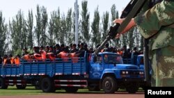 FILE - Criminals and suspects are transported to a stadium for a mass sentencing rally in Yili, Xinjiang Uighur Autonomous Region, May 27, 2014. 