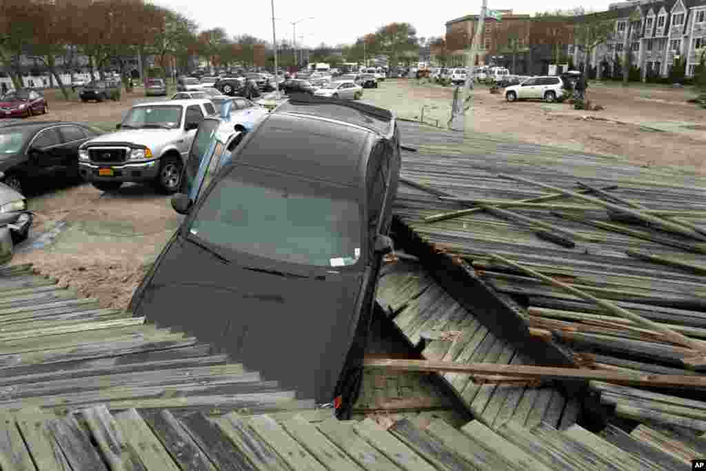 Des pi&eacute;tons passent &agrave; c&ocirc;t&eacute; de la promenade en boix et des voitures d&eacute;plac&eacute;es par Sandy &agrave; Queens, New York 