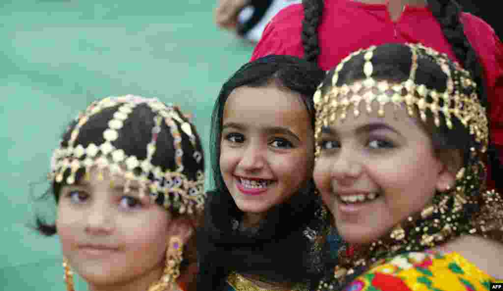Emirati girls in traditional outfit, usually worn in their village by elderly women, look on during the al-Gharbia Watersports festival near al-Mirfa beach outside Abu Dhabi.