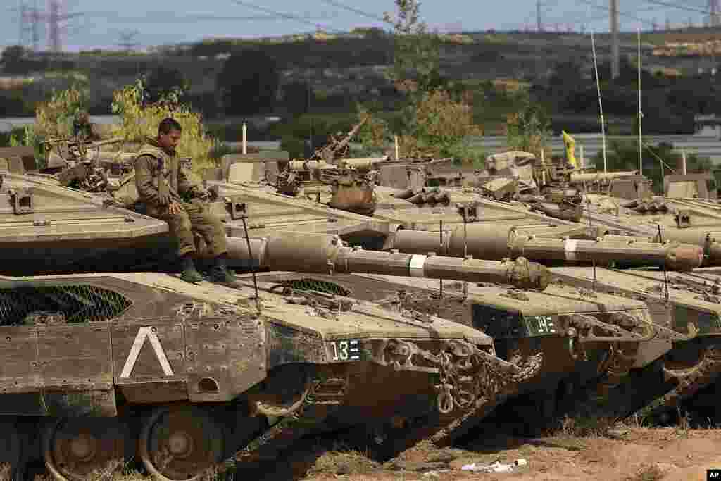 An Israeli soldier sits on top of a tank at a staging ground near the border with Gaza Strip, southern Israel, after a cease-fire took effect.