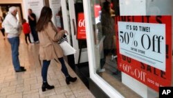 FILE - Discount signs stand in the window of a clothing store as last-minute shoppers finish up their Christmas gift lists at the Cherry Creek Mall in Denver, Dec. 24, 2018. 