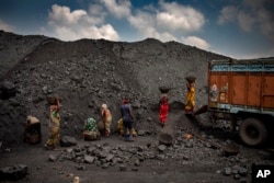 FILE - Indian laborers load coal into a truck in Dhanbad, an eastern Indian city in Jharkhand state, Friday, Sept. 24, 2021. (AP Photo/Altaf Qadri)
