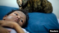 FILE - Samruei, a 35 year-old terminally ill Thai woman rests with her cat at a hospice for those dying of AIDS at a Buddhist temple Wat Prabat Nampu in Lop Buri.