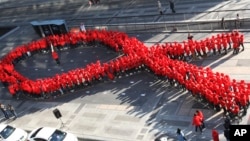 FILE - High school students make a formation in the shape of the red ribbon, the universal symbol of awareness and support for those living with HIV, during a campaign to mark World AIDS Day in Seoul, South Korea, Dec. 1, 2103. 