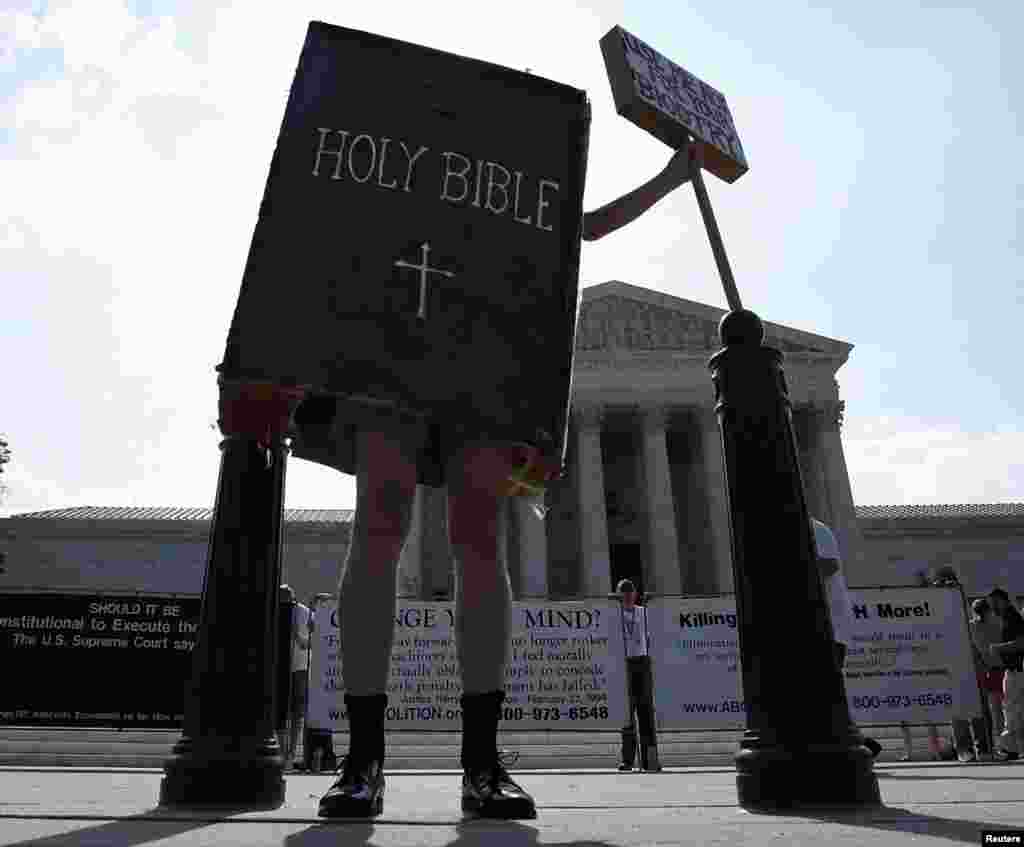 A protester dressed as a copy of the Bible joins other demonstrators outside the U.S. Supreme Court in Washington, June 30, 2014.