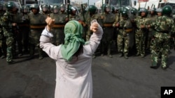 资料照：在西方记者访问乌鲁木齐一处地段之际，一名维吾尔妇女在中国武警面前要求释放被捕的维吾尔人。(2009年7月7日)