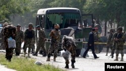 Para petugas memeriksa lokasi serangan bom bunuh diri yang menarget sebuah bus angkatan udara Afghanistan di Kabul (2/7). Delapan perwira dilaporkan tewas dalam insiden tersebut.