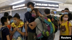 资料照片：香港一名妇女在香港机场前往英国前与家人分别（2021年6月30日）