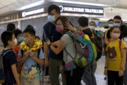 FILE - A woman reacts with her family member before departing to United Kingdom at the Hong Kong International Airport in Hong Kong, June 30, 2021.