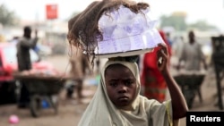 A girl sells drinking water packed in small plastic bags on a street in the northern city of Maiduguri, Nigeria, August 2009.