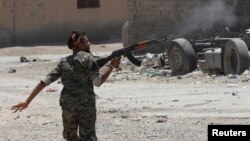A Kurdish fighter from the People's Protection Units (YPG) fires his rifle at Islamic State militants as he runs across a street in Raqqa, Syria, July 3, 2017.