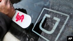 FILE - A Lyft logo is installed on a Lyft driver's car next to an Uber sticker in Pittsburgh, Jan. 31, 2018. The “gig” economy might not be the new frontier for America’s workforce after all.