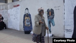 A bypasser looks at graffiti works by Yemeni artist Haifa Subay in Sanaa. The murals depict different facets of the conflict in Yemen, such as the horror of land mines and the demand for girls' education.