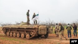 شورشیان سوری حین عبور از یک تانک که بیرق گروه تحریر الشام را در سوریه انتقال می دهد