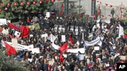 Protesters stand in front of riot police during a demonstration outside the parliamentary building in Tunis November 22, 2011.