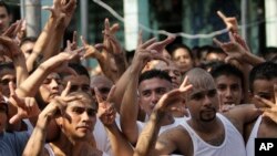 Miembros de pandillas hacen un gesto mientras asisten a una conferencia de prensa de sus líderes en una prisión en Quezatepeque, El Salvador. 