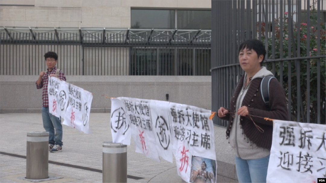 馬永田和她的兒子現身中國駐美國大使館門外拉橫幅抗議。(視頻截圖)