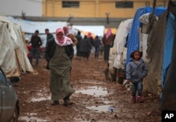FILE - Syrian walk at a camp near the Bab al-Salam border crossing with Turkey, in Syria, Feb. 6, 2016. Thousands of Syrians have rushed toward the Turkish border, fleeing fierce Syrian government offensives and intense Russian airstrikes.