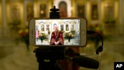 Un sacerdote de la Iglesia Ortodoxa habla a los fieles durante una transmisión de video en una vacía iglesia de Moscú, Rusia, el domingo 19 de abril de 2020.