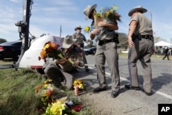 Law enforcement officials move flowers left at the scene of a shooting at the First Baptist Church of Sutherland Springs, Nov. 6, 2017, in Sutherland Springs, Texas.