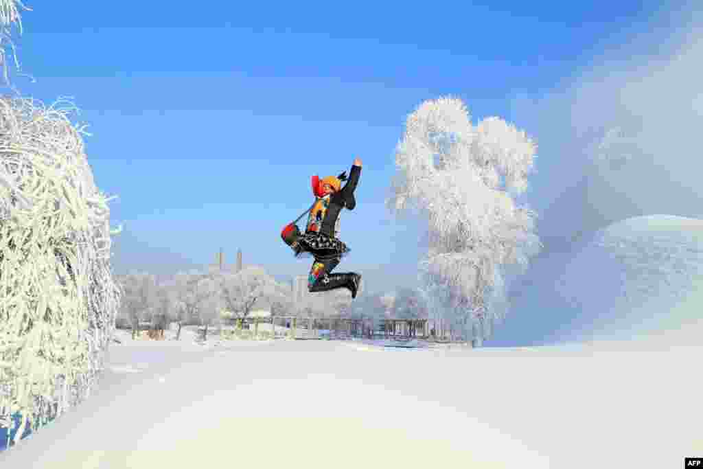 A woman poses for a photo by a snow-covered tree in Jilin, in northeast China&#39;s Jilin province.