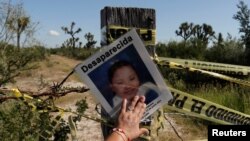 FILE - A picture of a missing woman is pictured during a mass with relatives of missing persons at the site where several bodies were found in mass graves in the municipality of Salinas Victoria, Nuevo Leon Mexico, October 29, 2016.