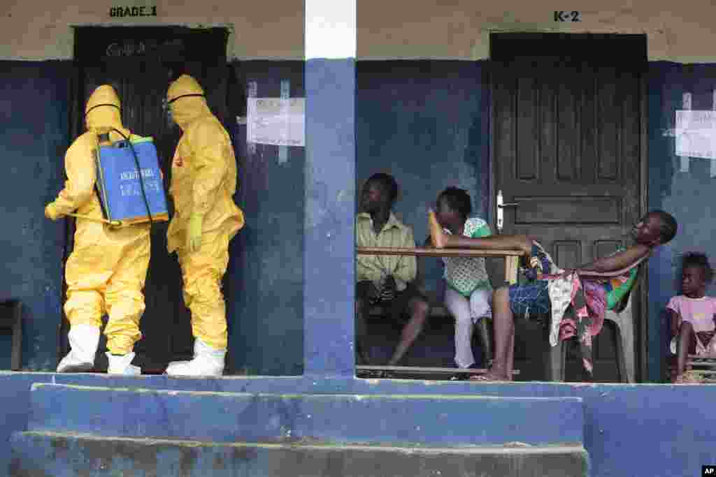 Residents of Freeman Reserve watch members of District 13 ambulance service disinfect a room as they pick up six suspected Ebola sufferers that had been quarantined, Sept. 30, 2014.