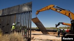 Construction workers are seen next to heavy machinery while working on new bollard wall in Santa Teresa, New Mexico, as seen from the Mexican side of the border in San Jeronimo, on the outskirts of Ciudad Juarez, Mexico, April 23, 2018. 
