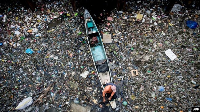 FILE - A worker collects garbage from the Marilao River in Bulacan, north of Manila, on March 18, 2017.