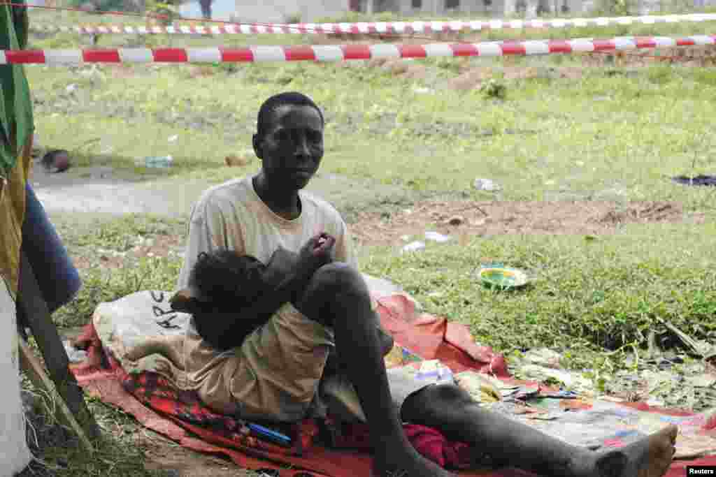 Suspected carrier of Ebola virus James Flomo sits in isolation with his child after his wife Lorpu Flomo died three days earlier in Monrovia, Liberia, Jan. 21, 2015.