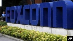 FILE - A security guard stands at the entrance of the Foxconn complex in the southern Chinese city of Shenzhen.