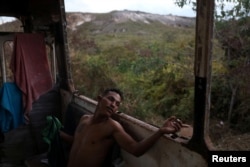 Venezuelan Hildemaro Ortiz relaxes inside of an abandoned bus in the border city of Pacaraima, Brazil, April 13, 2019.