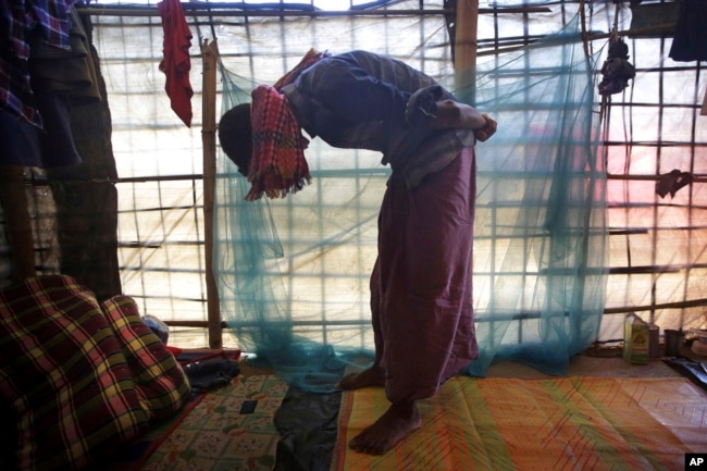 In this Nov. 27, 2017, photo, Mohamed Yaha, 18, demonstrates what he saw when soldiers bound the hands of dozens of men behind their backs with nylon rope and blindfolded them with scarves taken from the women when they massacred his village in Myanmar's Rakhine state.