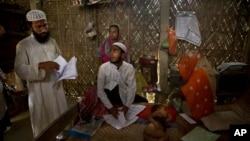 In this Thursday, Aug. 9, 2018 photo, Muslim farmer Abdul Mannan, 50, left, and Anuwar Hussain, 21, center, review the certificates of members of their family whose names were left out from the National Register of Citizens draft. (AP Photo/Anupam Nath)