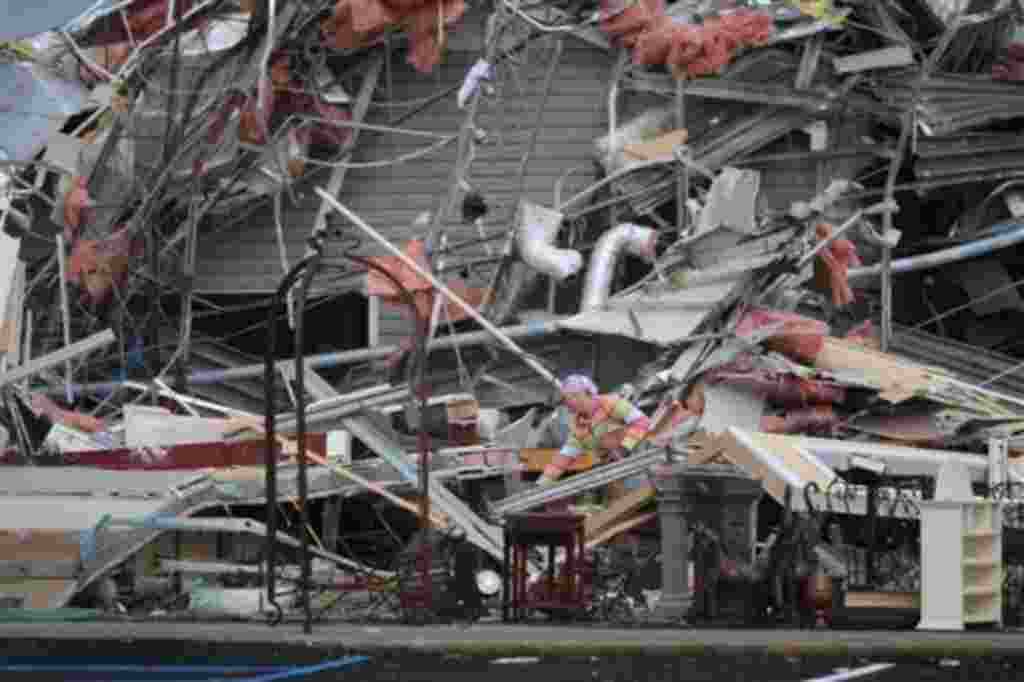 Una mujer contempla la destrucción de una antigua oficina de T Mobile después del tornado.