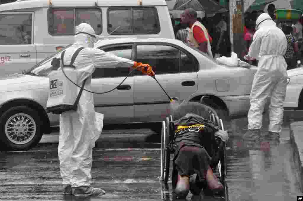 Health workers spray disinfectant on the body of a amputee suspected of dying from the Ebola virus, in Monrovia, Liberia, Sept. 2, 2014.