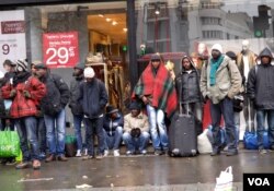 FILE - Migrants wait in the cold and rain to be bused to temporary shelters in Paris. (L. Bryant/VOA)