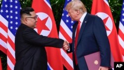 Pemimpin Korea Utara Kim Jong Un dan Presiden AS Donald Trump dalam pertemuan pertama di Singapura, 12 Juni 2018 - atau tepat setahun lalu (foto: dok). 