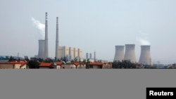 FILE - The cooling towers and chimneys from a coal-burning power station in a newly constructed residential area in Beijing.