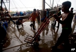FILE - Migrant workers unload frozen fish from a boat at a fish market in Samut Sakhon province, west of Bangkok, June 20, 2014.