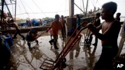 Migrant workers unload frozen fish from a boat at a fish market in Samut Sakhon Province, west of Bangkok, Friday, June 20, 2014. The United States had blacklisted Thailand and Malaysia for failing to meet its minimum standards in fighting human trafficking, a move that could strain relations with two important U.S. partners in Asia. Thailand had mounted a determined campaign to prevent a downgrade that could exact a cost toits lucrative seafood and shrimp industries for which America is a key market. (AP Photo/Sakchai Lalit)