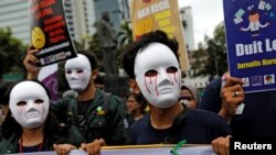 Para wartawan menggunakan topeng saat mengikuti pawai tahunan Hari Buruh Internasional atau May Day dekat Monas, Jakarta, Indonesia, 1 Mei 2019.