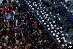 Polisi Turki mengenakan baju anti huru-hara (kanan) menghadang para pengunjuk rasa dalam demonstrasi menentang kekerasan gender di pusat Kota Istanbul, Turki, 25 November 2018.