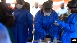 Health care workers from the World Health Organization prepare to give an Ebola vaccination to a front-line aid worker in Beni, Democratic Republic of Congo, Aug. 10, 2018. 